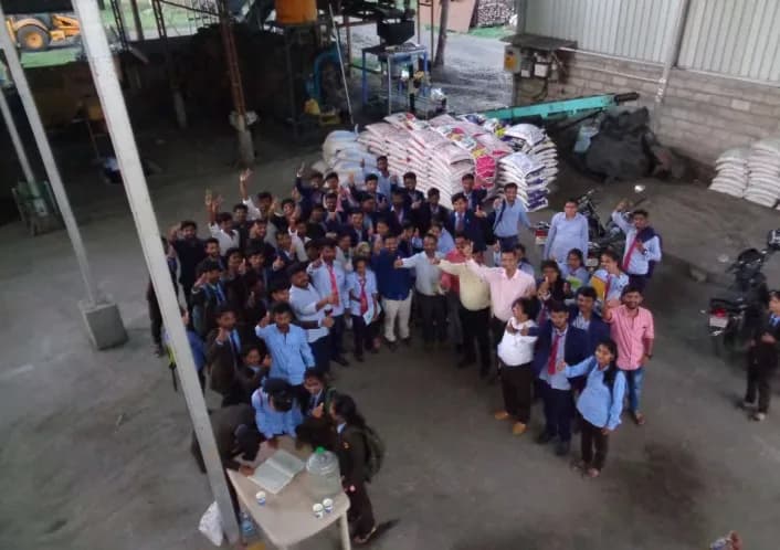 Students visiting the manufacturing yard, with bags of product stacked behind them